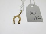 un gros plan sur un pendentif en forme de fer à cheval en or, sur lequel est accrochée une étiquette de prix