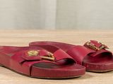 pair of women ' s red leather sandals with gold buckles on a wooden surface
