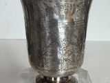 un vase en argent posé sur un socle transparent, sur une table