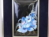 painting of a blue flower in a black frame on a white surface