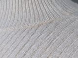 a close up of a white sweater with buttons on it