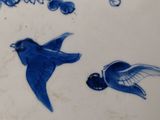 a blue and white plate with birds and flowers on it