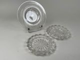 trois assiettes en verre et une horloge posées sur une table