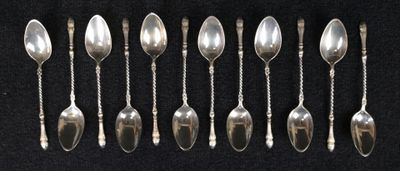 six cuillères en argent sont disposées en rangée sur une surface noire