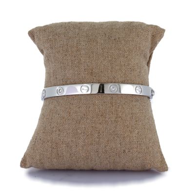 un gros plan d'un bracelet en argent posé sur un oreiller, sur fond blanc
