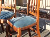 three wooden chairs sitting in front of a building