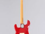 a red electric guitar hanging from a string on a gray background