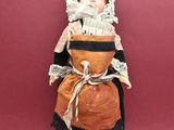 an antique doll of a woman in a dress and bonnet