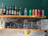 many bottles and glasses on a shelf above a sink