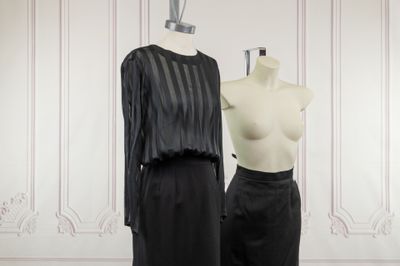 two mannequins in front of a white wall and a black dress on a mannequin stand