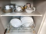 de nombreux plats et tasses sur les étagères du placard