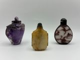 trois bouteilles en verre de couleurs différentes posées les unes à côté des autres sur une surface blanche