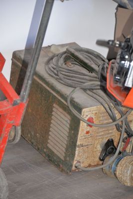 a small machine that is sitting on the floor next to a red cart
