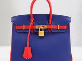 un sac à main bleu et rouge muni d'un cadenas sur la poignée