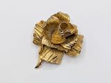 a gold flower brooch on a white surface