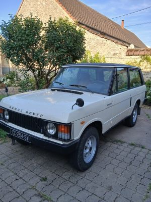 un Land Rover blanc garé devant une maison