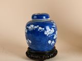un vase bleu orné de fleurs blanches, posé sur un socle