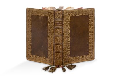 un vieux livre surmonté d'un pompon, posé sur une surface blanche