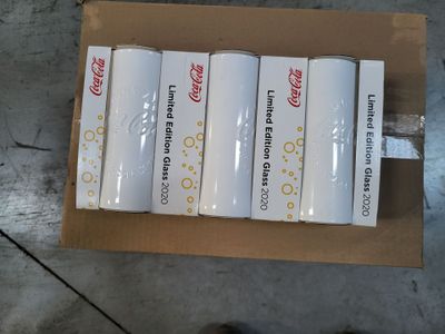 six canettes de Coca-Cola posées sur une boîte en carton