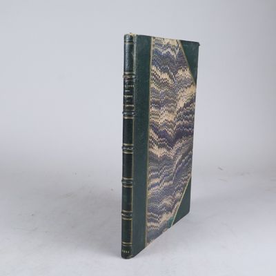 un vieux livre à la couverture verte posé sur une surface blanche