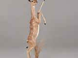 statue d'une gazelle debout sur ses pattes arrière, tenant un bâton dans la bouche