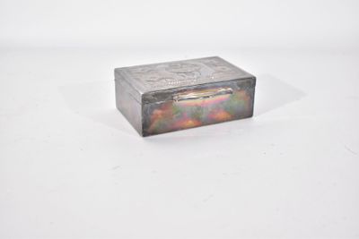 une vieille boîte en argent posée sur une surface blanche
