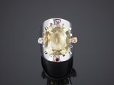 un gros plan d'une bague sertie d'une topaze jaune entourée de pierres multicolores