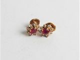 a pair of red and gold earrings on a white surface
