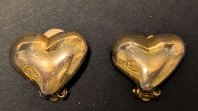 deux boucles d'oreilles dorées en forme de cœur posées sur un fond noir