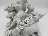 une figurine représentant une femme assise sur un lit avec des chiens