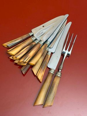 five knives and a fork on a red surface