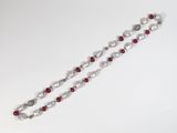 a close up of a white and red beaded necklace on a white surface