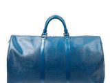 un sac de voyage bleu posé sur une surface blanche
