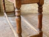 a wooden table with a wooden top on a brick floor