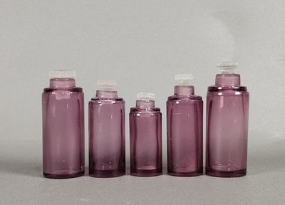 four purple bottles are lined up in a row on a white surface