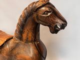a wooden rocking horse with a saddle on it ' s back