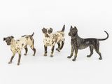 three figurines of dogs standing in a line on a white surface