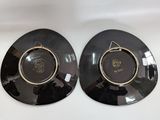 two black plates with gold trims on them