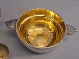 a silver bowl with a spoon and a spoon rest on a table