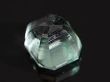 un gros plan d'un quartz vert posé sur une surface noire