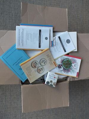 une boîte en carton remplie de livres et de papiers, posée par terre