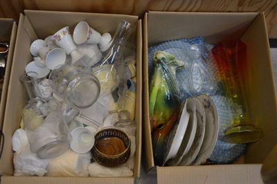 deux boîtes contenant des assiettes et des bols, posées sur une table