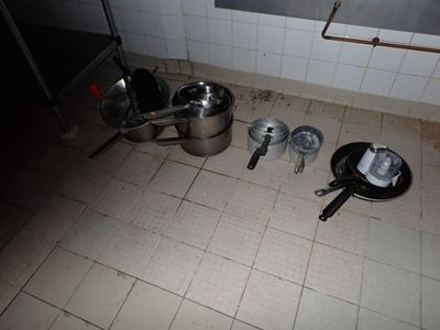 des casseroles et des poêles par terre dans une cuisine