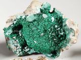 a green piece of rock with some rocks in the background