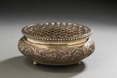 an ornate silver box with a lid on a gray surface