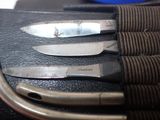 three knives sitting on top of a piece of leather