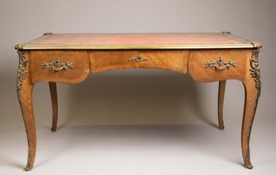 un bureau ancien en bois, muni de deux tiroirs et d'un plateau orné d'une plaque en laiton