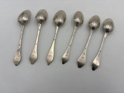 six silver spoons are lined up in a row on a white surface