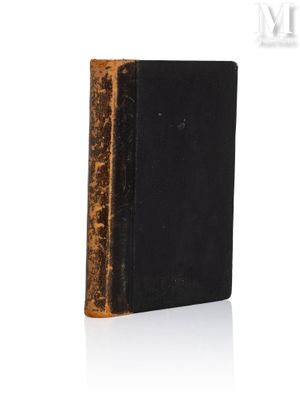 un vieux livre à la couverture noire posé sur une surface blanche