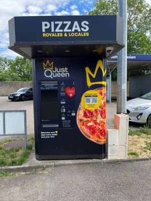 un distributeur automatique sur lequel est posée une pizza